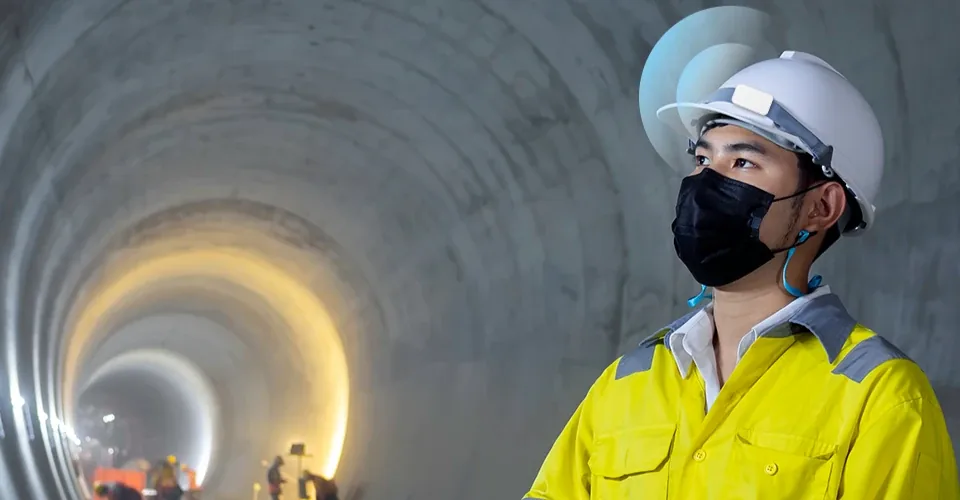 A tunnel engineer wearing a white hard hat with a beacon tag